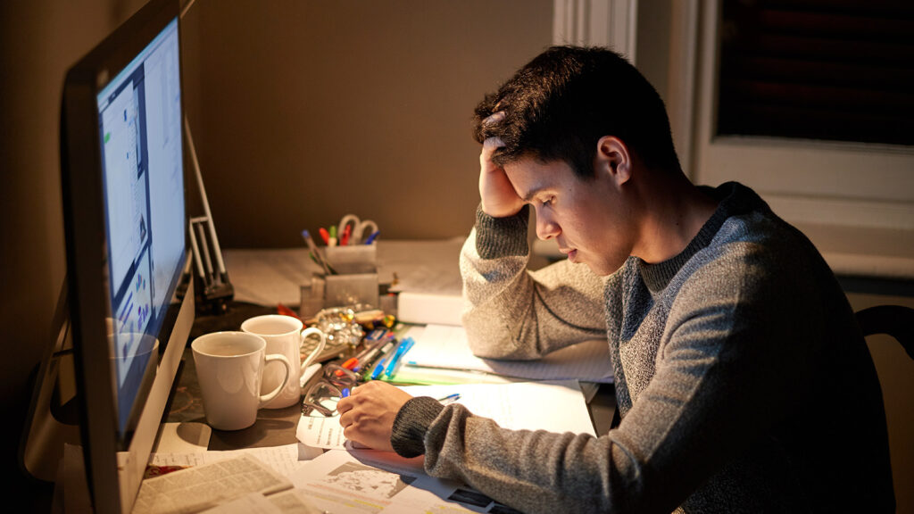 Person studying late into the night due to an exam the following day. This illustrates the negative effects of cramming for an exam like AP Pre-Calc has on the body.