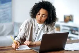 A student sitting down actively completing her homework assignments, showing her time management abilities.